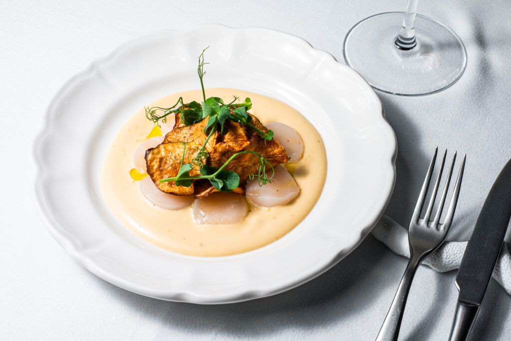 Corona Solar, un carpaccio de vieira con emulsión de yuzu y crujiente de tupinambo. Corona Solar, un carpaccio de vieira con emulsión de yuzu y crujiente de tupinambo.