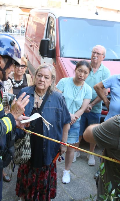 Un bomber amb veïns afectats per l'esvoranc del Putxet. © Miquel Codolar / ACN