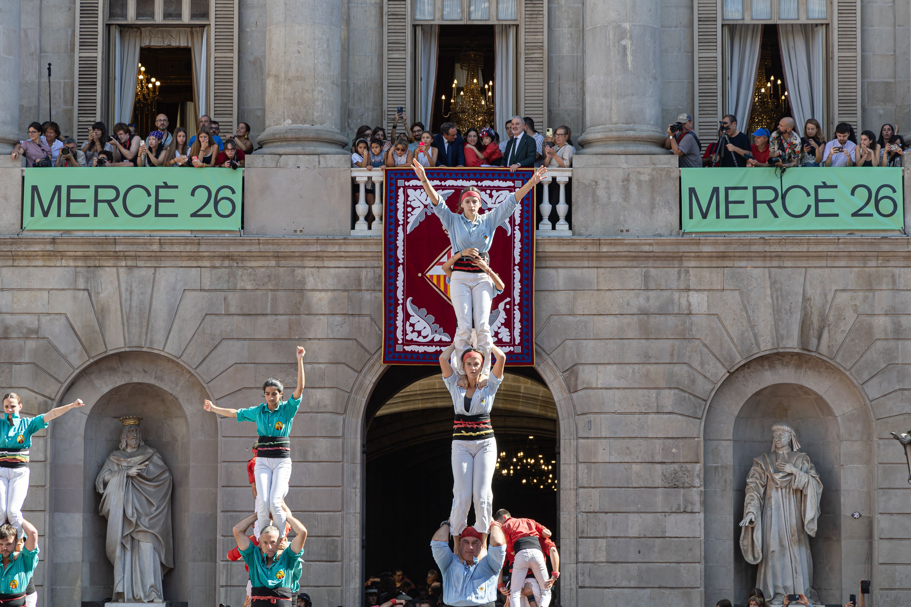 Els Castellers aixequen els seus pilars davant l’Ajuntament, amb l’anxaneta al balcó. © Àngel Bravo