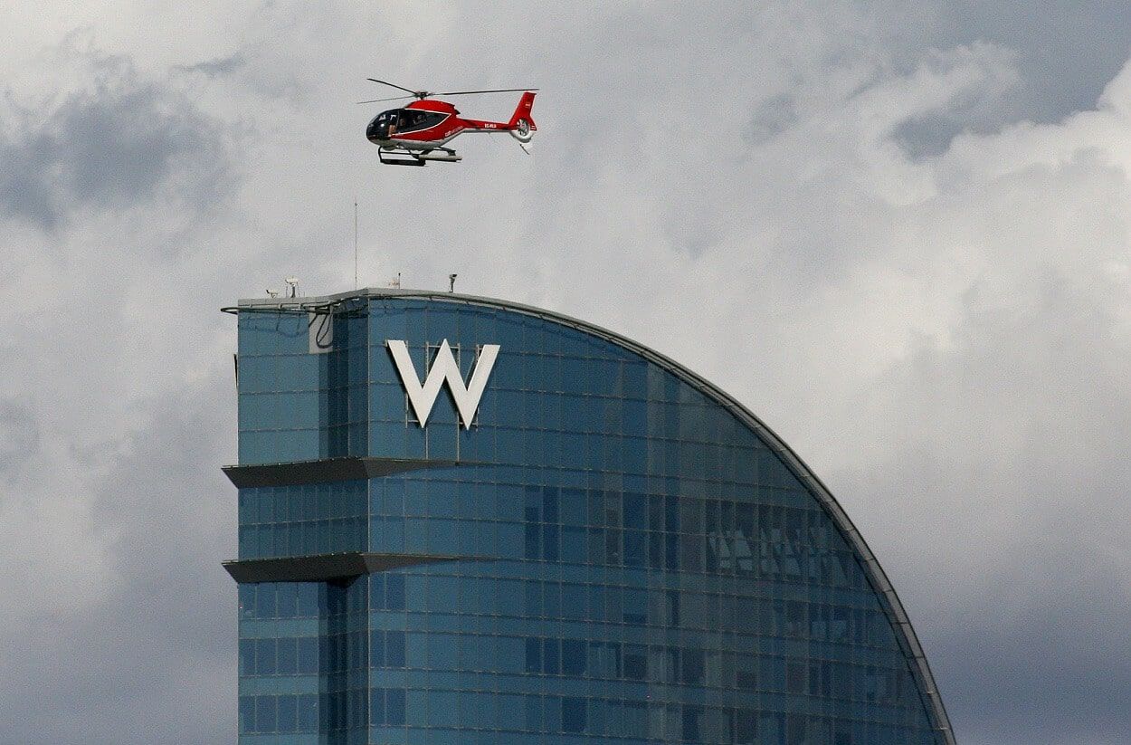 Un helicóptero Colobri pasa junto al W Barcelona tras despegar del helipuerto del puerto de Barcelona (Javier Ortega Figueiral)