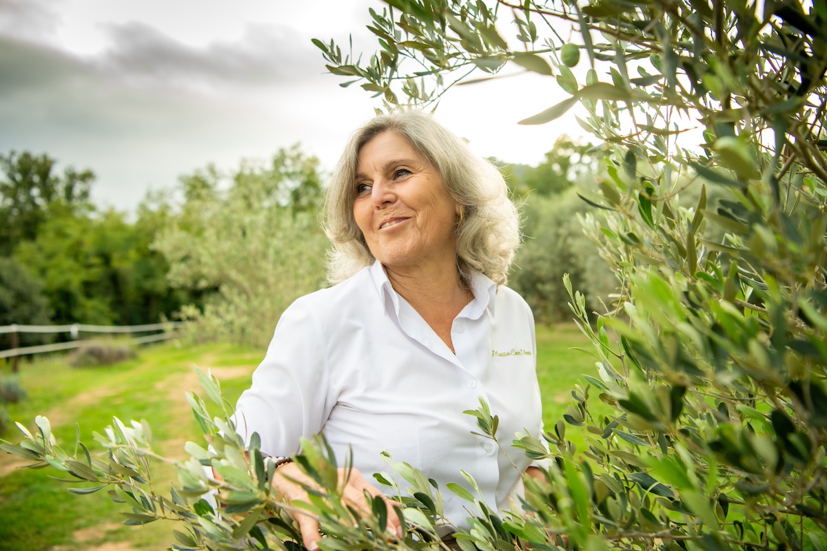 Rosa Mª Pérez passejant entre les oliveres de varietat vera que han contribuït a recuperar, per Sergio Ros